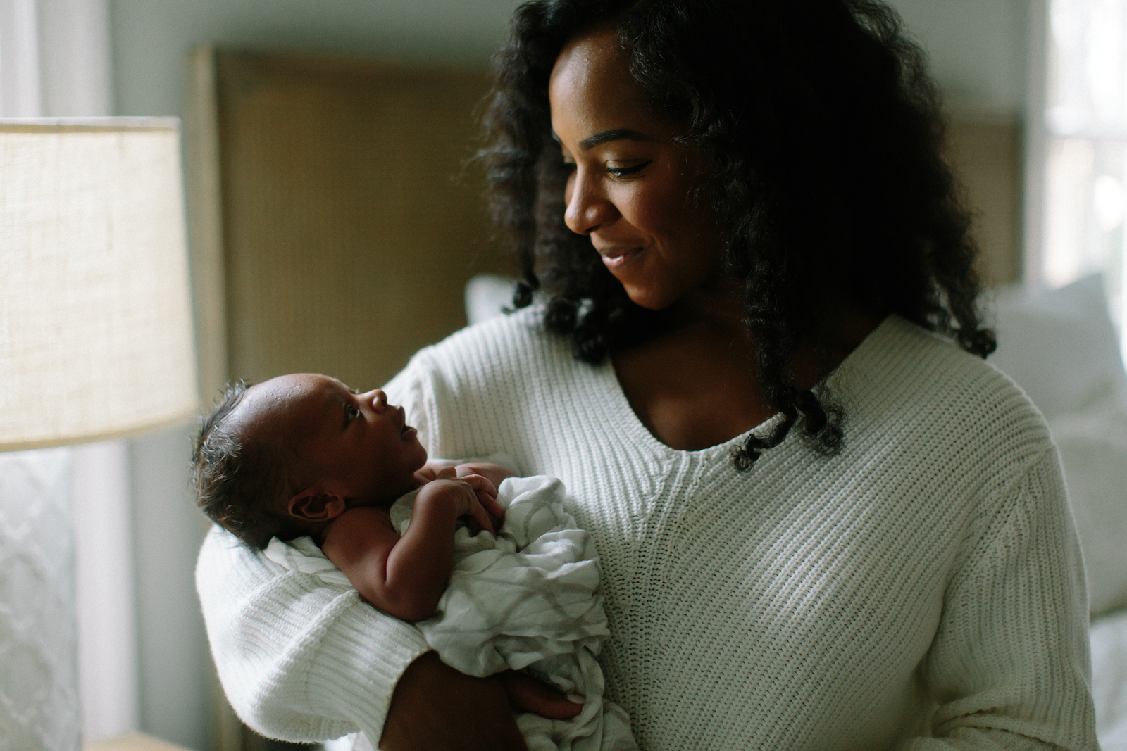 Photo of a mother and her newborn baby. She is cradling him in her arms and smiling at him. Located in Charlotte, North Carolina.